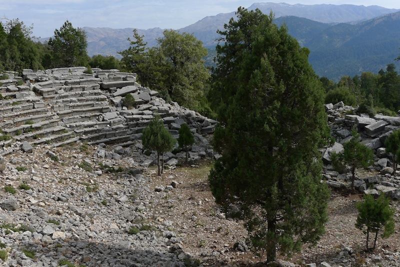 The theater ruins of Oinoanda Ancient City and the ancient fortification walls seen through the pine forests.