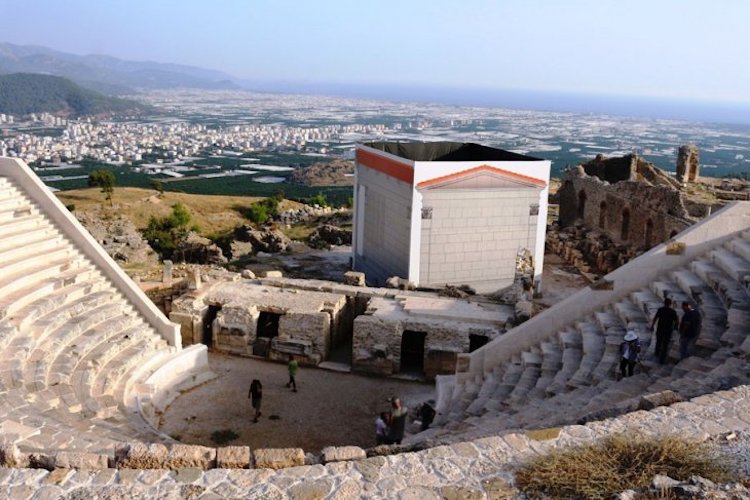 The Hellenistic-planned theater of Rhodiapolis Ancient City located on the steep slope overlooking the Kumluca Plain, with the restored stone blocks of the monumental Opramoas Inscription right next to it.