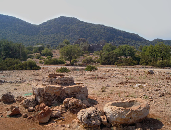 The ruins of the Doric Temple of Apollo at the rugged summit of Tyberissos Ancient City, with the Çevreli Plain and Kekova Gulf landscape stretching in the background.