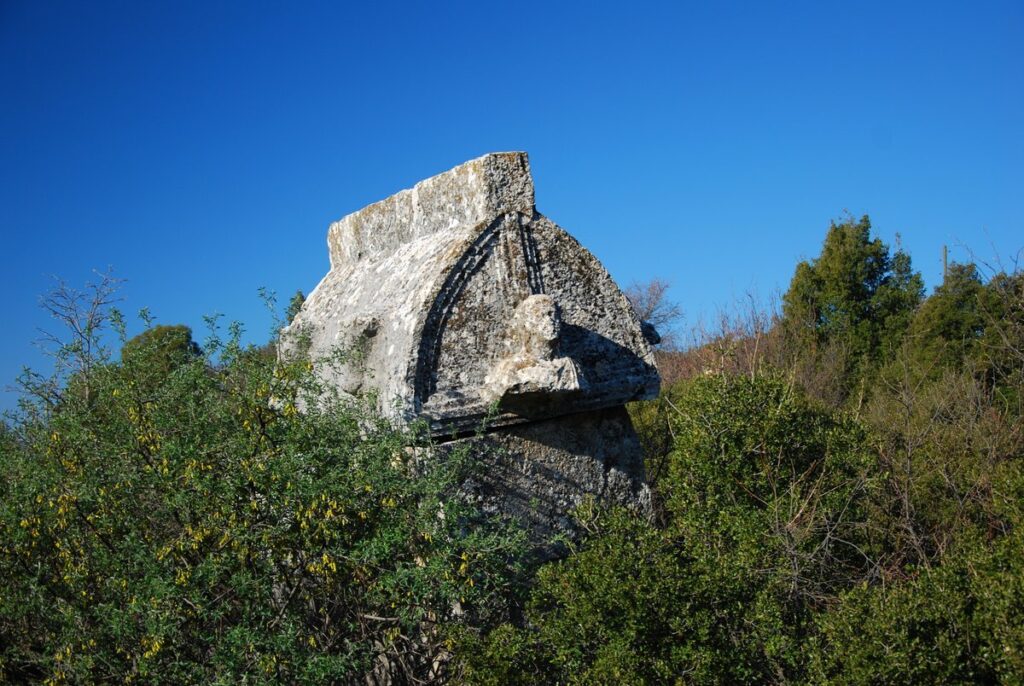 The remaining monumental foundation walls of the famous Trysa Heroon (which was transported to Vienna) on the rugged acropolis of Trysa Ancient City, surrounded by traditional Lycian sarcophagi.